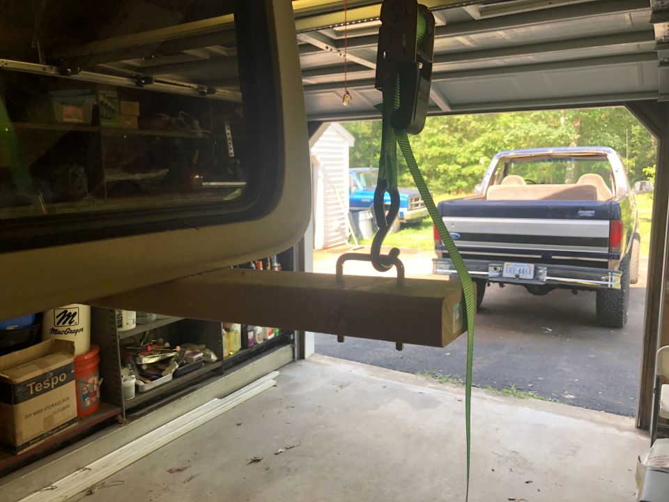 Rear view of a blue and silver Ford Bronco with a tan interior, parked in a garage