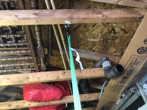 1995 Ford Bronco - Attic storage area with an exhaust pipe and a green strap hanging from the rafters.