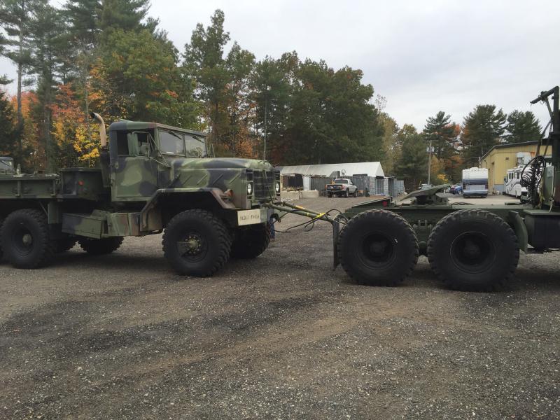 Camouflaged military truck towing a trailer, side view