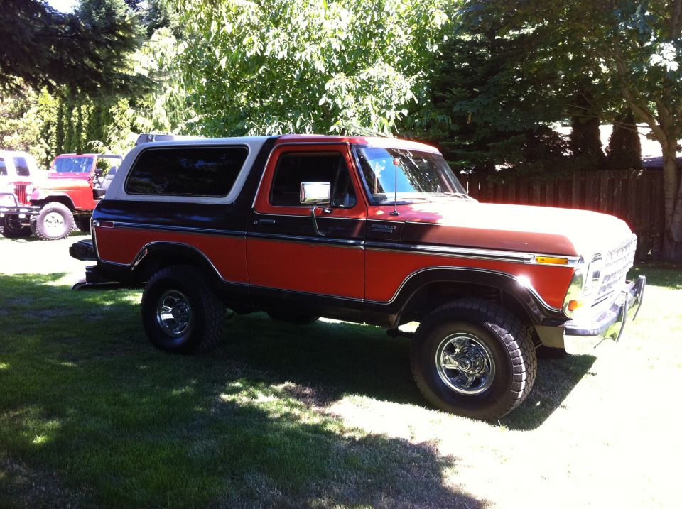 1978 Ford Bronco parked on grass with another red Jeep in the background