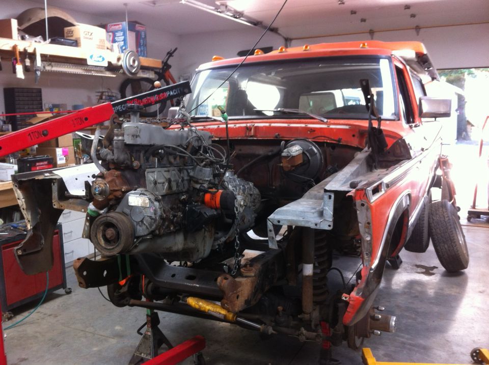 1978 Ford Bronco with engine being removed by an engine hoist in a garage