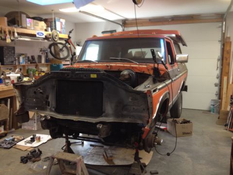 1978 Ford Bronco - Front end of an orange and black 1978 Ford Bronco disassembled in a garage setting.