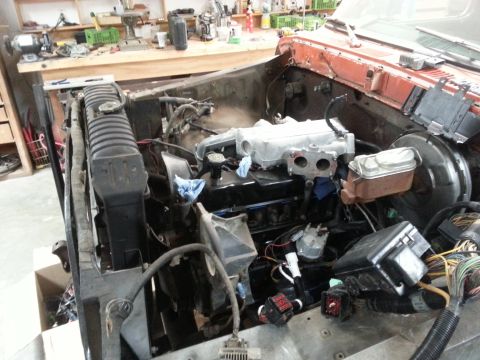 1978 Ford Bronco - The engine bay of a 1978 Ford Bronco, showing the radiator, engine block, and various wiring and plumbing components.