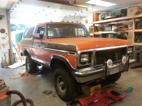 1978 Ford Bronco - Orange and brown 1978 Ford Bronco parked in a garage, showing its front 3/4 profile.