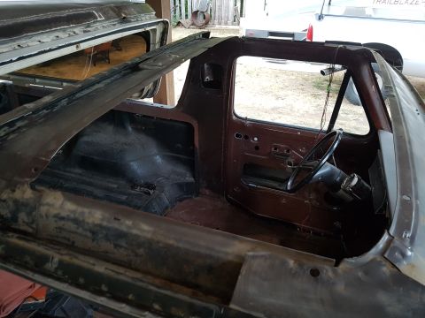 1978 Ford Bronco - The interior of a classic Ford truck is shown with its doors removed and body panels disassembled for restoration.