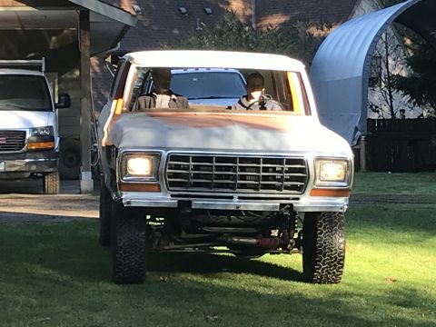 1978 Ford Bronco - Front view of a 1978 Ford Bronco with a prominent grille and headlights. Figures are seated inside.