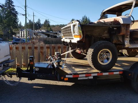 1978 Ford Bronco - 1978 Ford Bronco body on trailer, front end partially visible. Transporting vehicle.