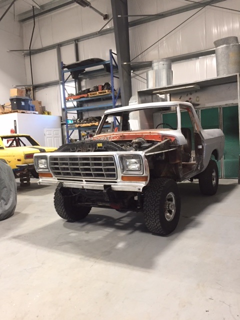 1978 Ford Bronco - A Ford F-Series truck is undergoing work in a garage, with its hood open and doors removed.