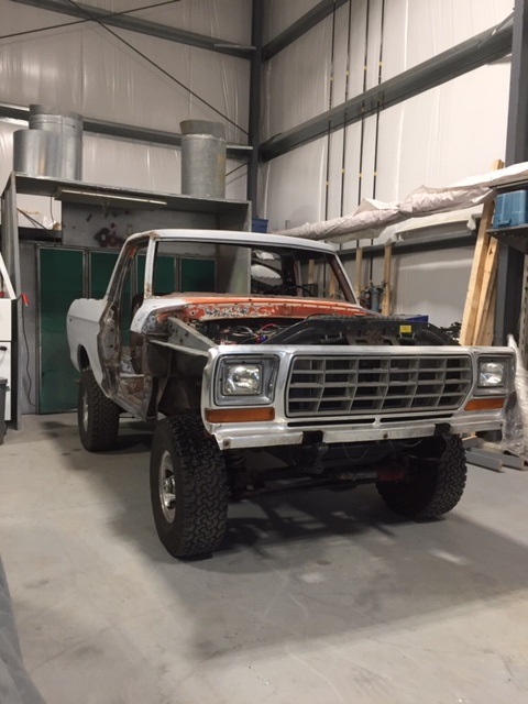 1978 Ford Bronco - This Ford F-Series truck, likely a 1979 model, is undergoing repairs in a workshop, with its hood open and doors detached.