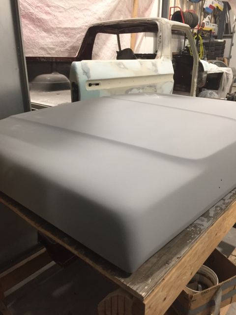 1978 Ford Bronco - Primer-coated hood and cab of a 1979 Ford F-Series truck in a workshop.