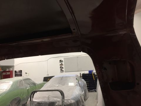 1978 Ford Bronco - A workshop scene showing the interior of a vehicle undergoing repairs, with two other cars covered in protective plastic sheeting.