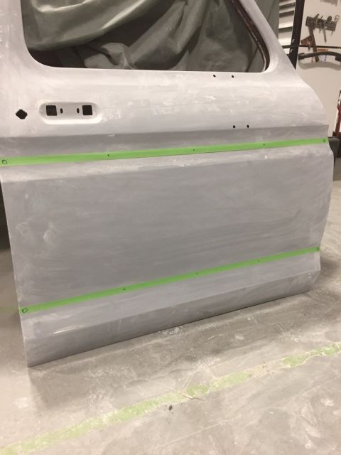 1978 Ford Bronco - A car door is shown with primer and green masking tape, indicating it's undergoing bodywork.