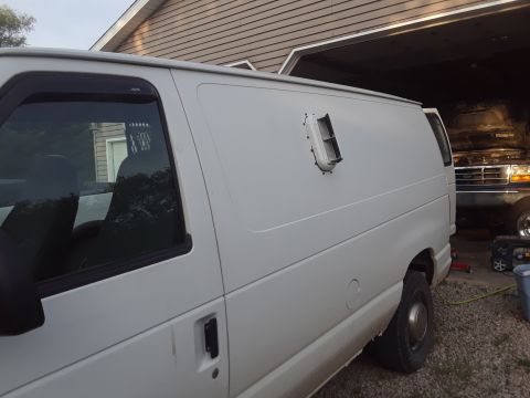 1999 Ford E250 - Side view of a white cargo van, with a blue pickup truck visible in the background.