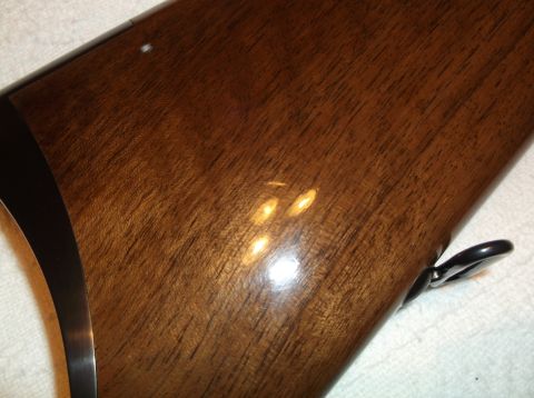 1995 Mercury Grand Marquis - The glossy wood grain of a firearm's stock is visible, with a metal swivel near the bottom.