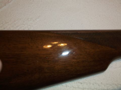 1995 Mercury Grand Marquis - Close-up of a wooden gun stock, showing the grain and a textured grip pattern.