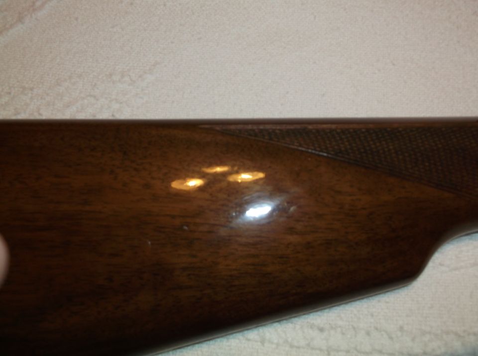 Wooden gun stock with glossy finish and textured grip area