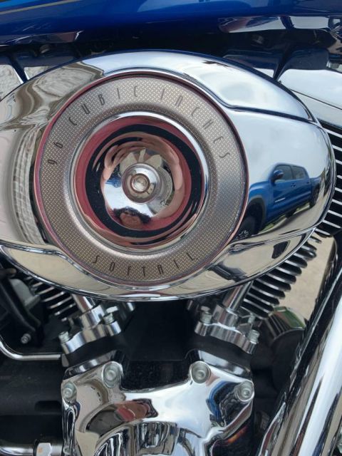 2008 Harley-Davidson Softail - Close-up of a Harley-Davidson Softail engine, a chrome air cleaner cover that reflects a blue pickup truck.