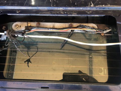 1995 Ford Bronco - Close-up of the rear window mechanism and wiring, showing signs of wear and damage.
