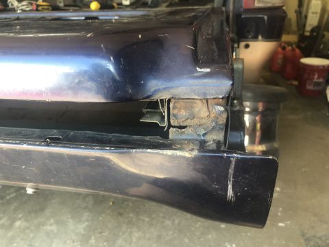 1995 Ford Bronco - The rear corner of a dark blue vehicle shows extensive rust and structural damage.