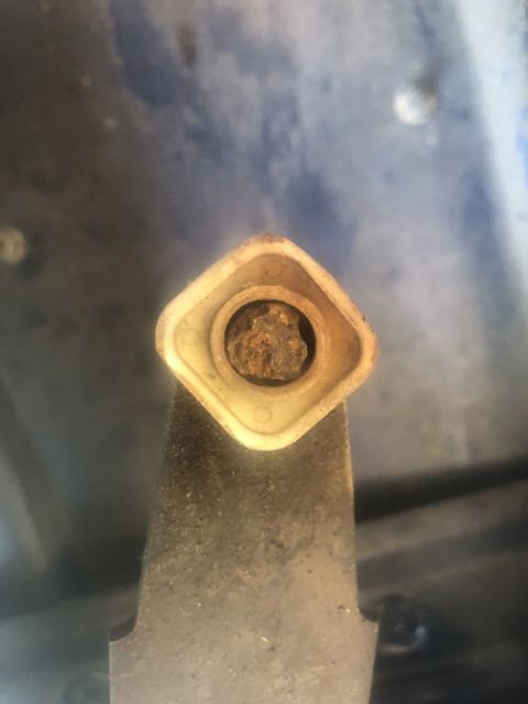 1995 Ford Bronco - A close-up view of a corroded bolt secured within a plastic mounting bracket.