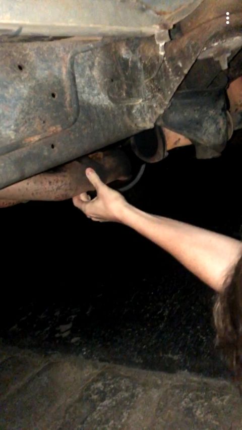 1988 Ford Bronco - A hand reaches out to touch the exhaust pipe of a vehicle's undercarriage. The Supermotors.net logo is visible at the bottom of the frame.