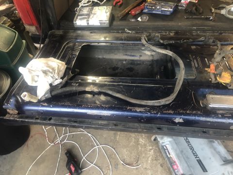 1995 Ford Bronco - The interior of a blue tailgate is shown with wiring and tools, suggesting repair work.