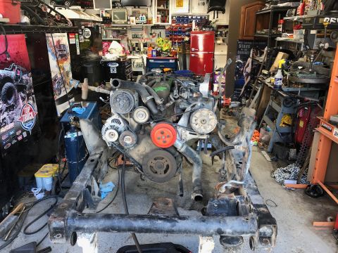 1992 Jeep Wrangler - Engine and chassis frame assembly in a cluttered garage workshop with tools and equipment visible.