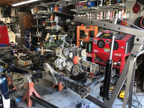 1992 Jeep Wrangler - A Jeep Wrangler chassis and engine are disassembled in a garage.