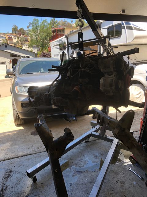 1992 Jeep Wrangler - Engine and transmission assembly removed from a vehicle and suspended by an engine hoist for service.