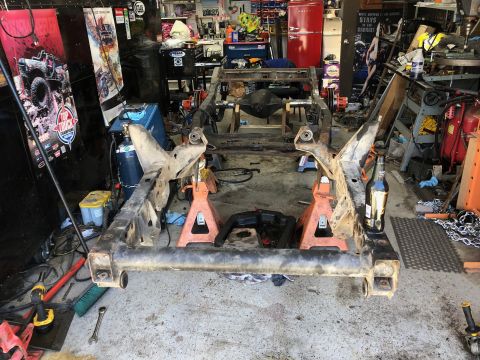 1992 Jeep Wrangler - Jeep Wrangler frame assembly undergoing work in a cluttered garage environment.
