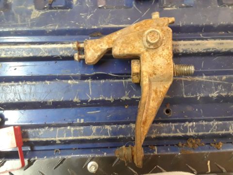 1994 Ford Bronco - A rusty metal bracket, possibly a brake or clutch component, is shown against a blue, ribbed surface.