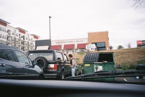 1988 Ford Bronco - A person stands by the driver's side door of a black Ford Bronco parked near dumpsters.