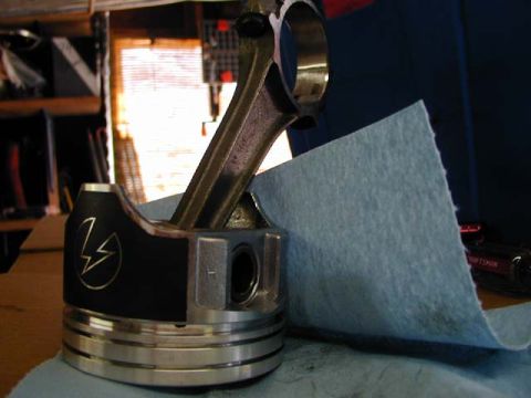 1979 Ford Bronco - A custom piston with a lightning bolt logo is shown with its connecting rod, placed on a shop towel.