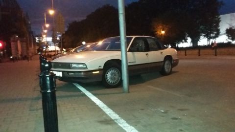 Cream-colored 1990 Buick LeSabre sedan parked at an angle, with a pole in front of it