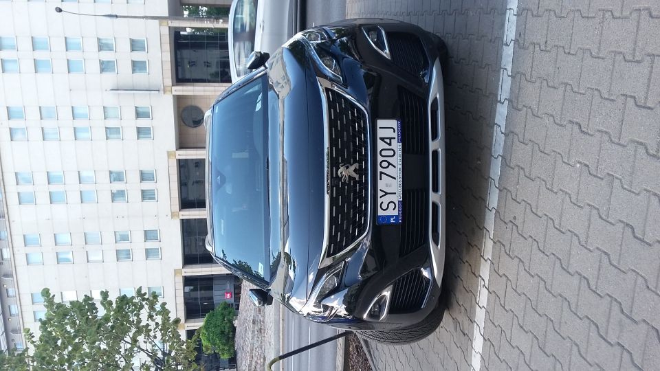 Black Peugeot SUV with license plate SY 7904J parked on a paved surface in front of a modern building