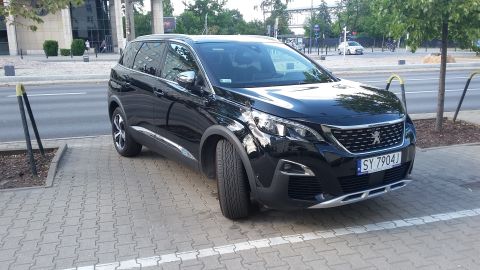 Black Peugeot SUV parked on a paved area next to a street. License plate reads SY 7904J
