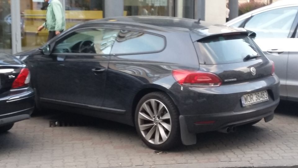 Dark gray Volkswagen Scirocco parked on a street, rear 3/4 view