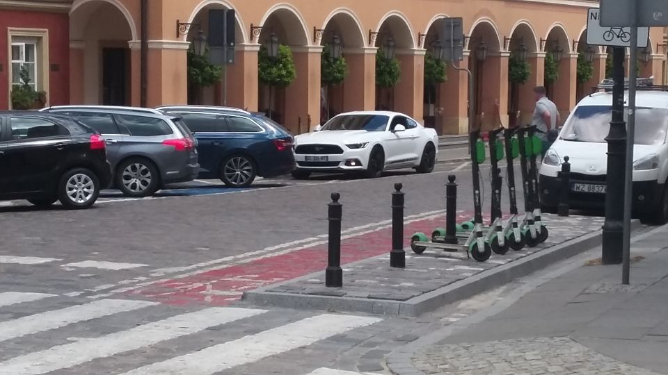 White Ford Mustang parked on street with other cars and scooters nearby
