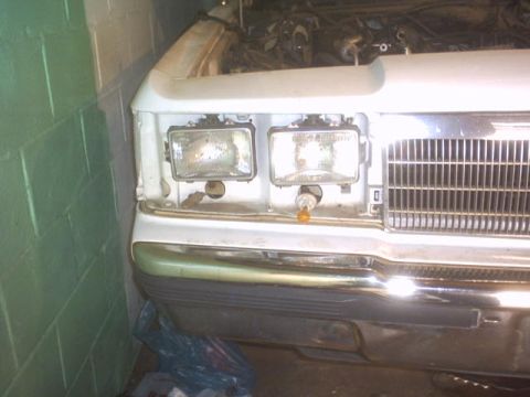 1991 Ford LTD Crown Victoria - The front end of a 1991 Ford Crown Victoria shows its headlights, grille, and exposed engine bay.