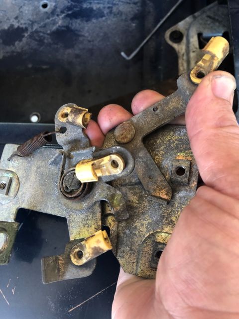 1995 Ford Bronco - Close-up of a vehicle's tailgate latch mechanism being held by a hand, showing internal components and wear.