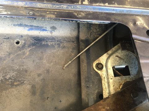1995 Ford Bronco - Close-up of a vehicle's internal tailgate latch mechanism, showing a detached cable and worn metal components.