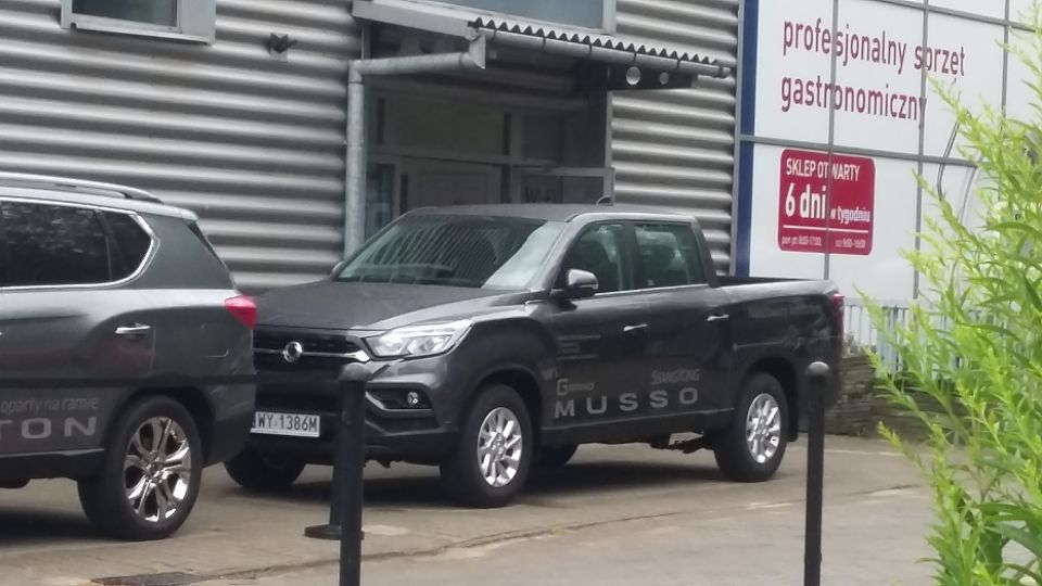 Dark gray SsangYong Musso pickup truck parked next to a dark gray SUV