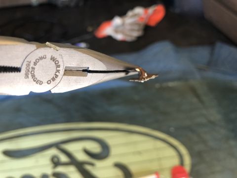 1995 Ford Bronco - Pliers are used on a Ford emblem, possibly for repair or modification.