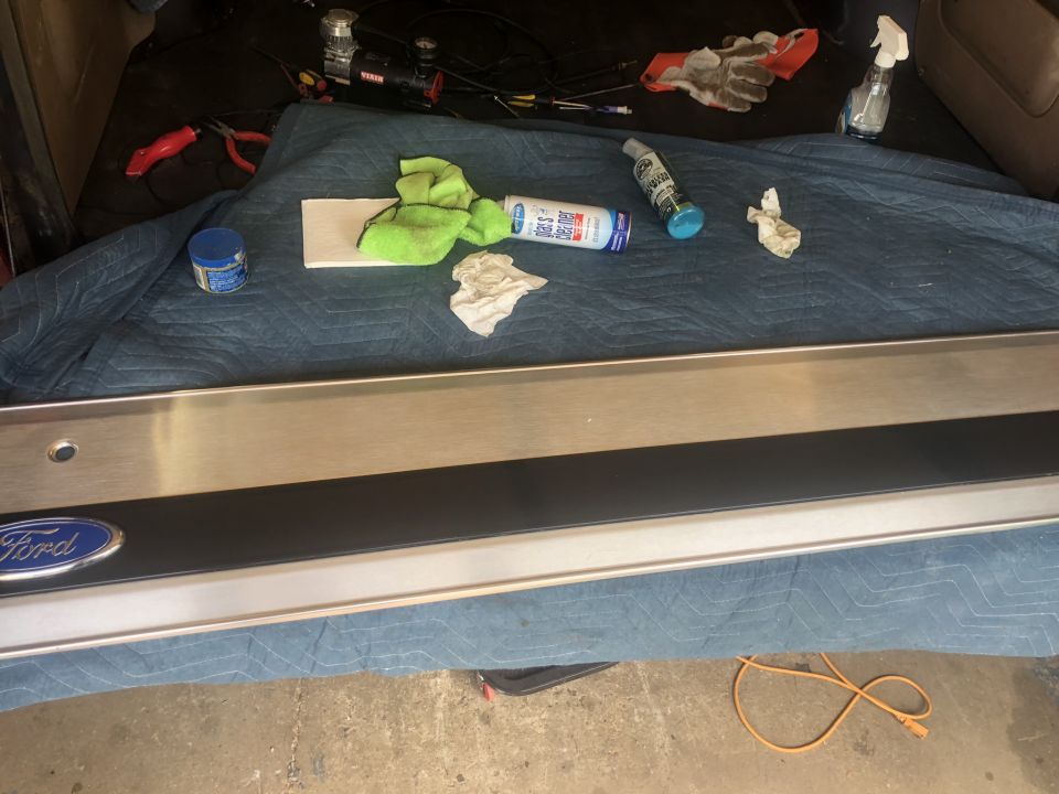 Ford tailgate trim with blue oval badge, tools, and cleaning supplies