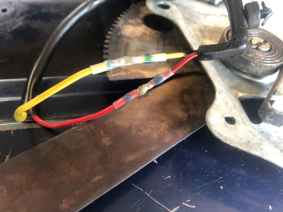 Close-up of red and yellow wires connected to a metal mechanism, likely part of a car window regulator
