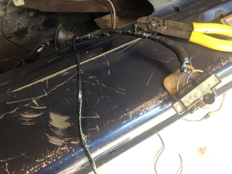 1995 Ford Bronco - Close-up of vehicle tailgate wiring being repaired with electrical tape and tools.