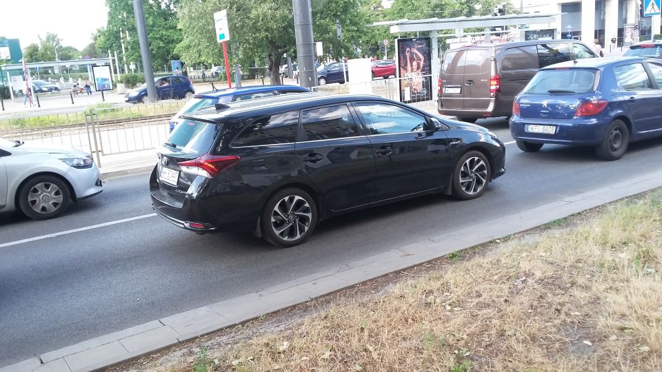 Black station wagon driving on a street with other cars around