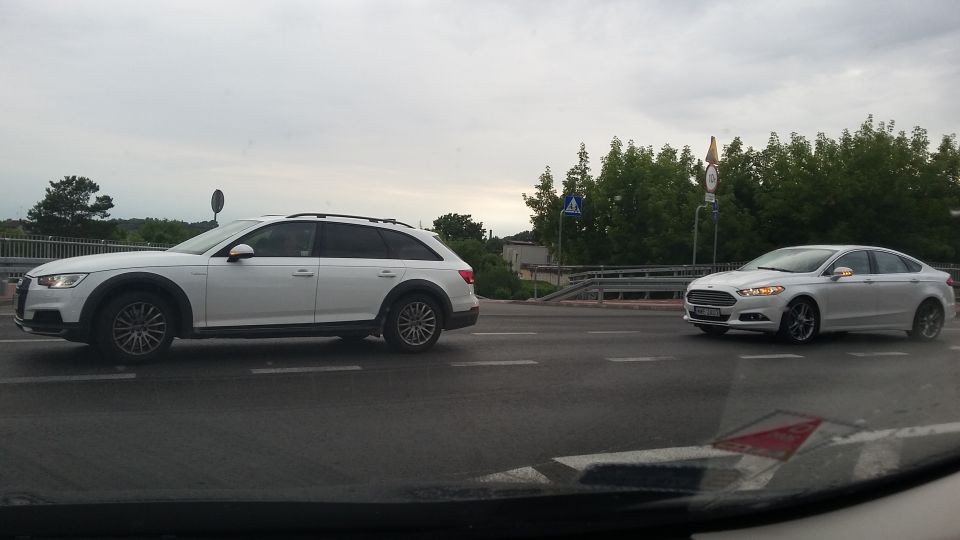 Two white cars on a road, one is an Audi A4 Allroad wagon, the other is a Ford Fusion sedan
