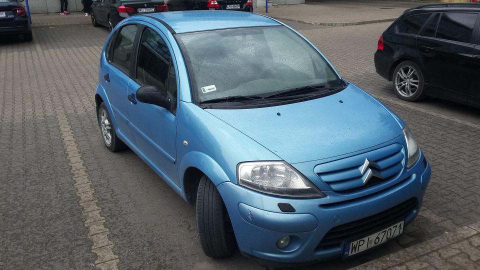 Blue Citroen C3 parked on a paved lot with a black SUV behind it