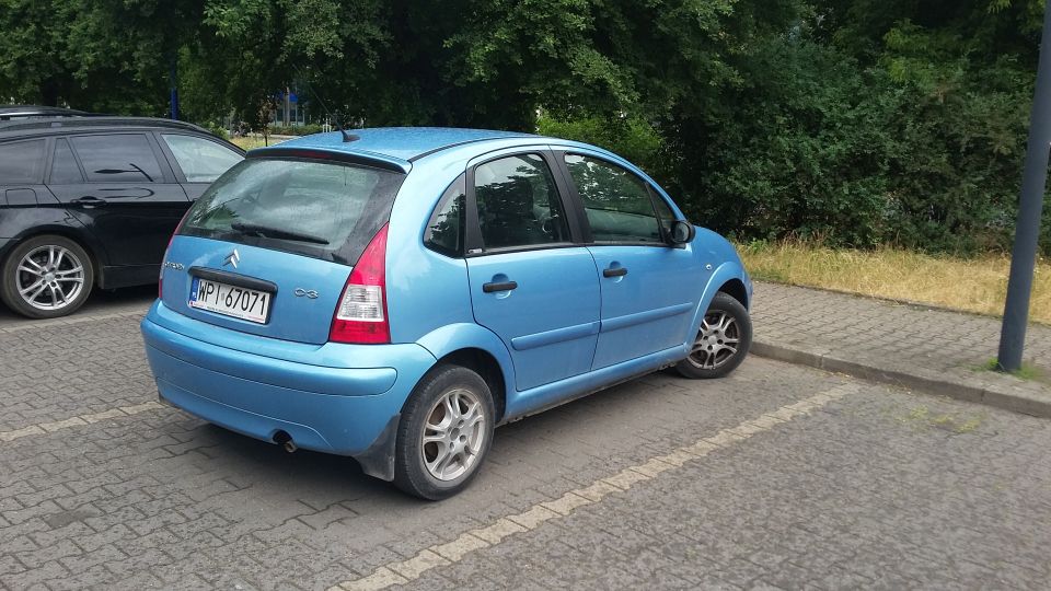 Blue Citroen C3 parked next to a black SUV. License plate is WP1 67071